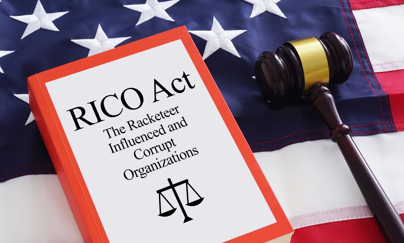 RICO Act book and gavel resting on the American flag, symbolizing racketeering charges and legal matters related to the Racketeer Influenced and Corrupt Organizations Act.