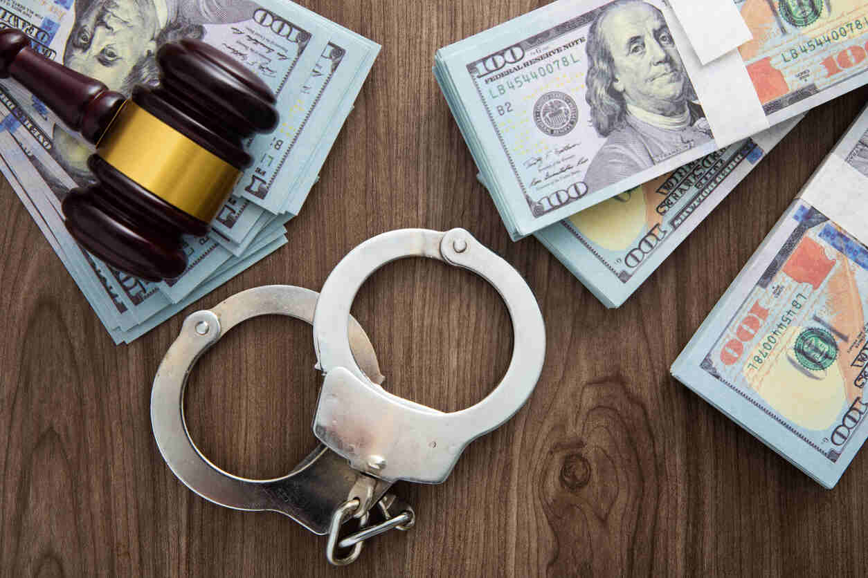 A close-up shot of several stacks of rolled-up hundred-dollar bills, held together by rubber bands. This image represents the financial assets involved in money laundering and highlights the risks of federal investigations for financial institutions and clients.