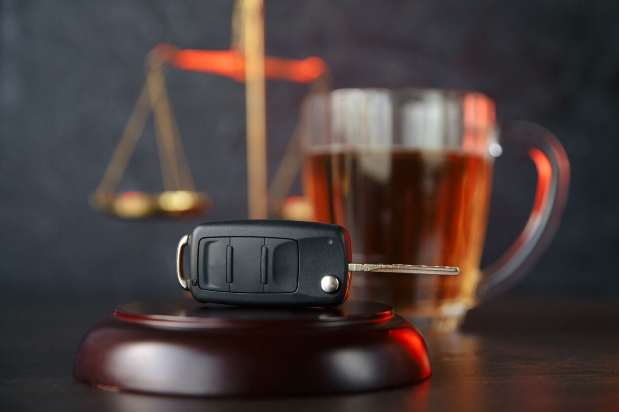 Car keys on a judge's gavel with a blurred glass of beer and scales of justice in the background, symbolizing DUI legal issues in Tampa.