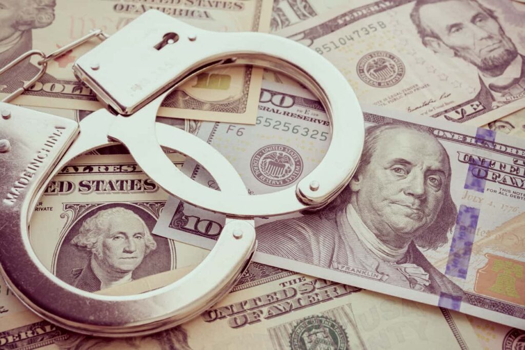 Handcuffs placed on U.S. dollar bills symbolizing financial crimes, federal investigations, and national security risks